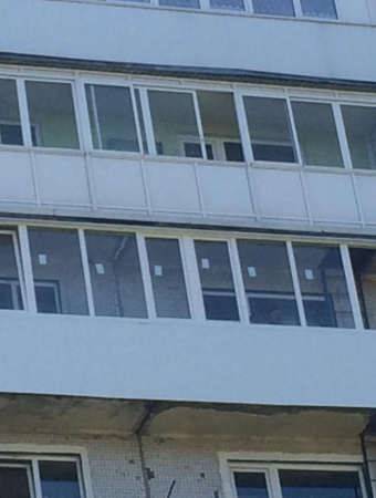 Длинный балкон с обшивкой пластиковыми панелями и остеклением